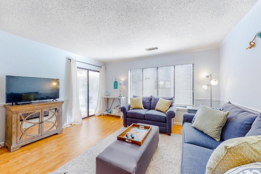 Una sala de estar con un sofá azul y un televisor. en Springwood Villas 51, en Hilton Head Island