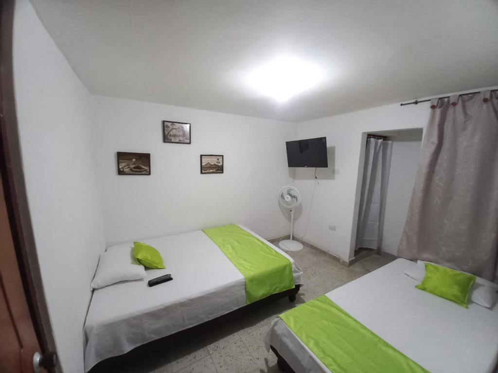 una camera con 2 letti, lenzuola verdi e TV di villa de las palmas a Palmira