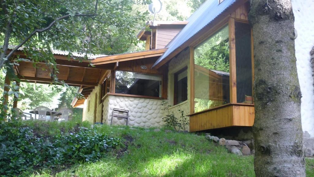 una casa con ventanas de cristal y un árbol en Casa Los Robles en San Martín de los Andes