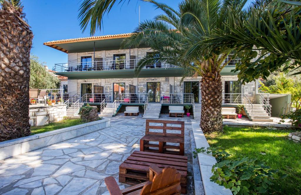 a house with benches and palm trees in the yard at Marti Resort in Skala Sotiros