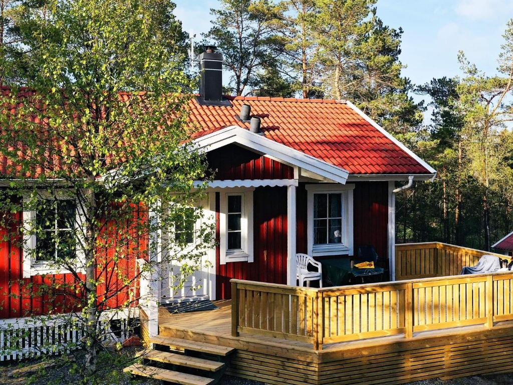 una pequeña casa roja con terraza de madera en Holiday home Grebbestad X en Grebbestad