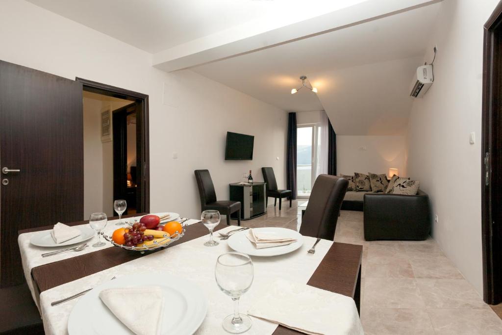 a dining room and living room with a table and chairs at Guest House Aria in Herceg-Novi