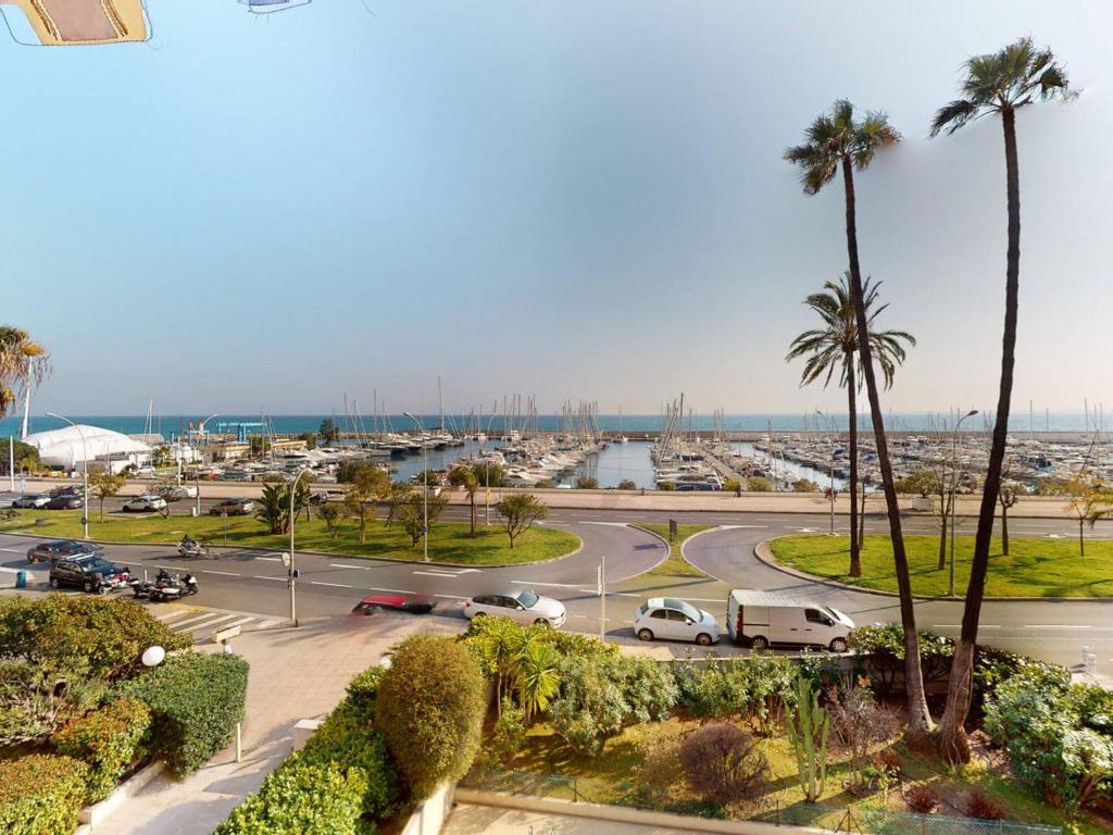 a view of a parking lot with palm trees and a harbor at Bel appartement avec terrasse, piscine, parking et WiFi - FR-1-196-321 in Menton
