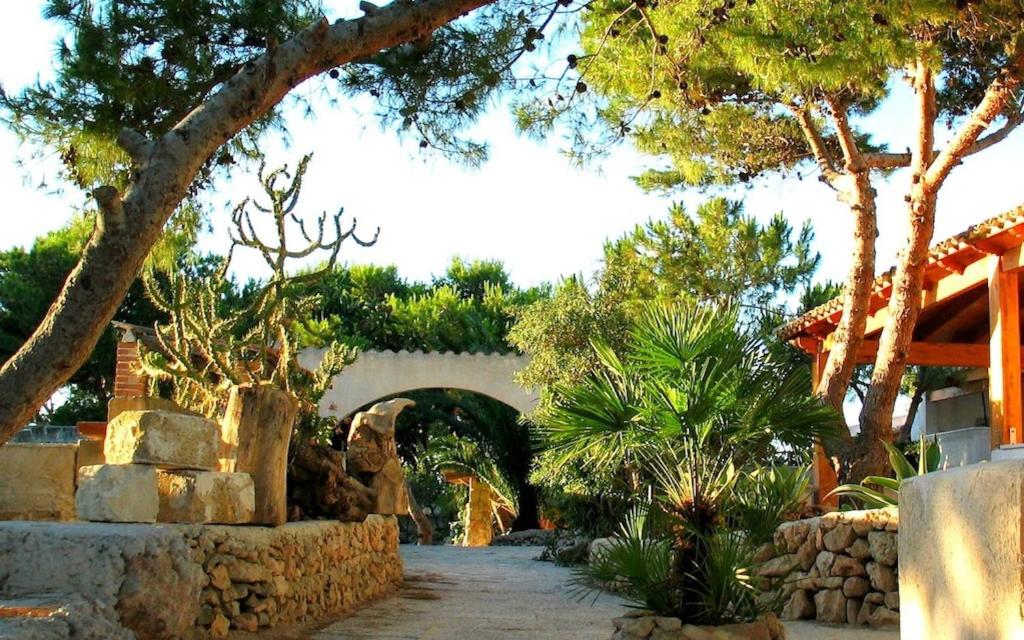 un jardín con un arco con árboles y plantas en La Torretta en Favignana