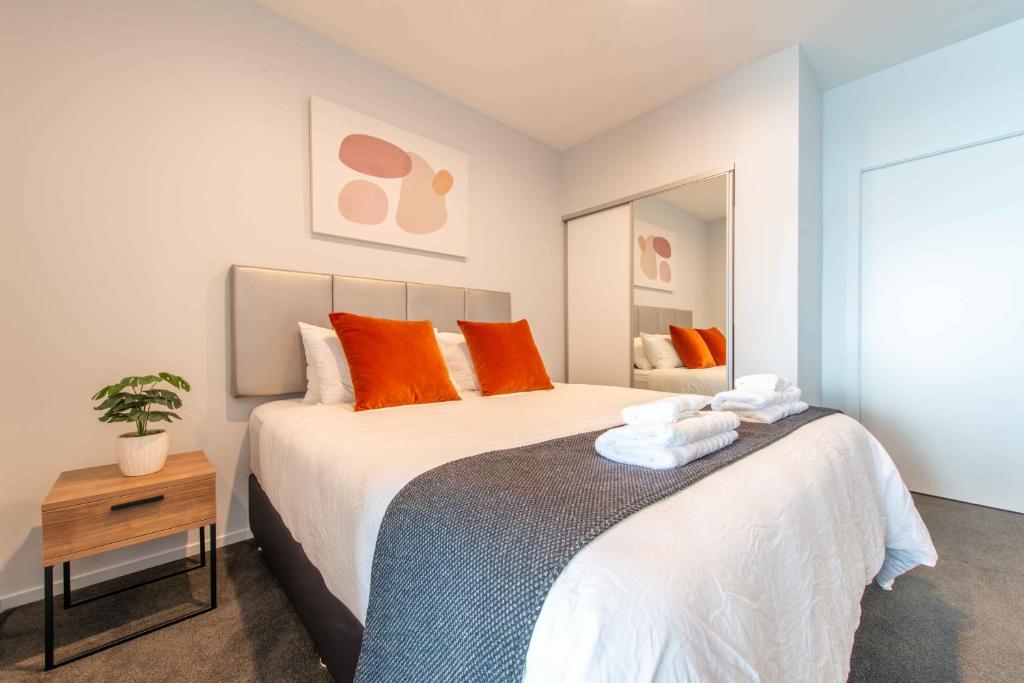 a bedroom with a large bed with orange pillows at Deluxe One Bedroom Apartment in Newmarket Auckland in Auckland