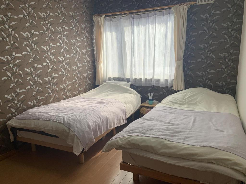 two twin beds in a bedroom with a window at STAY Sakura in Bibai