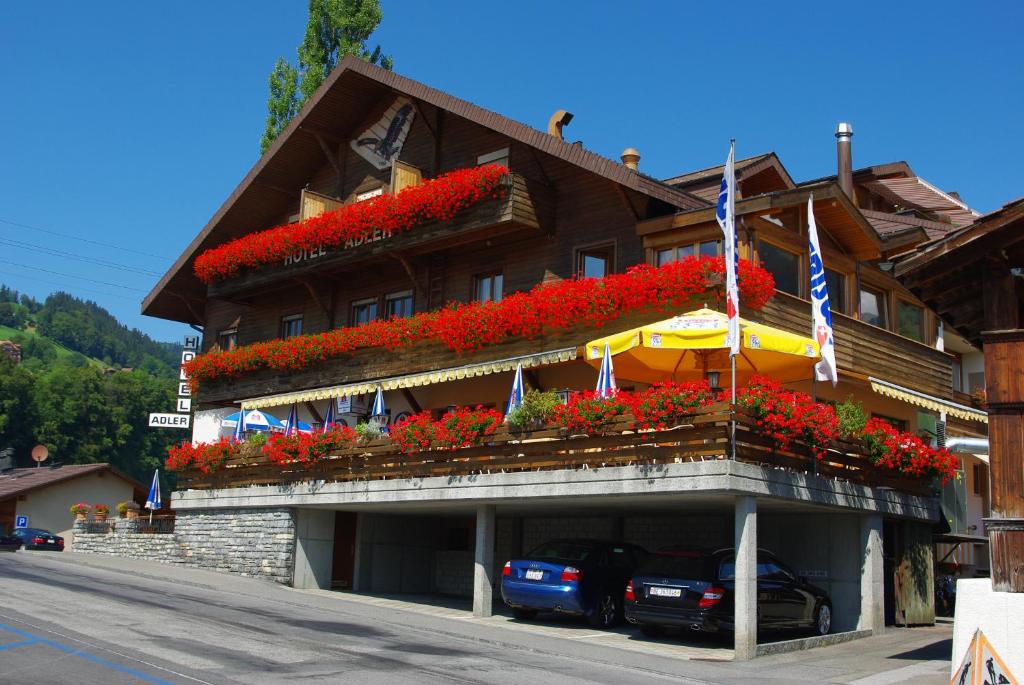 a hotel with red flowers on the front of it at Hotel Adler in Sigriswil