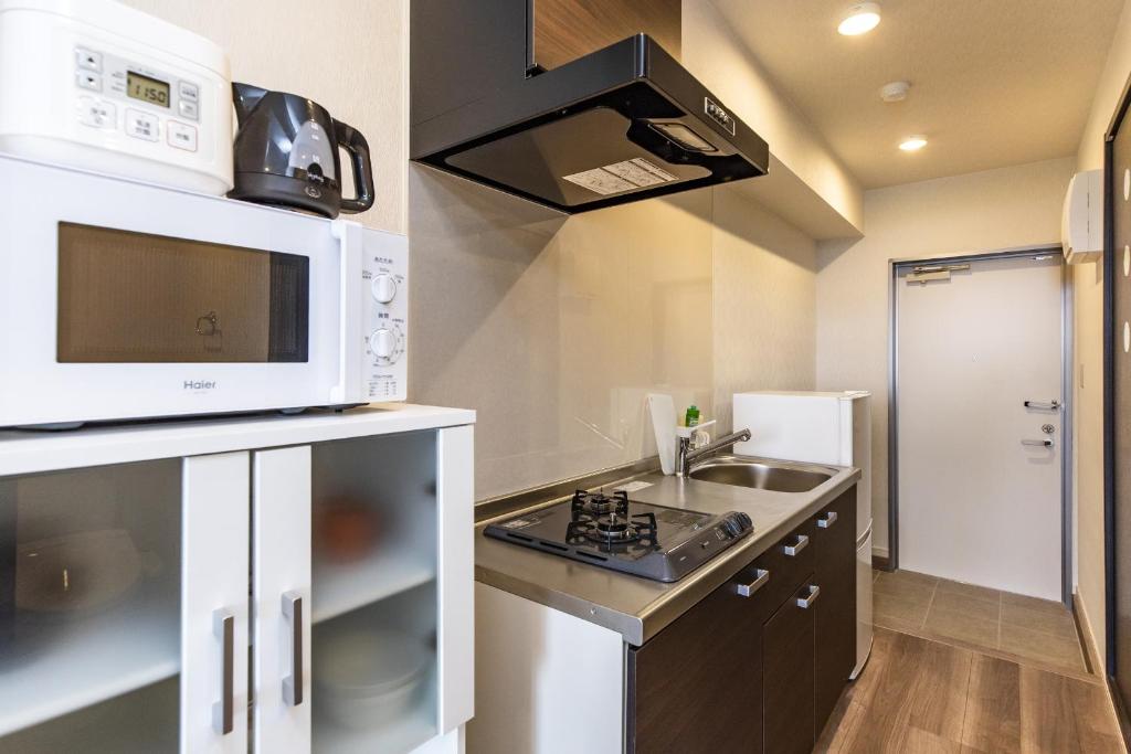 a small kitchen with a microwave and a sink at Yukurina Resort Okinawa in Motobu