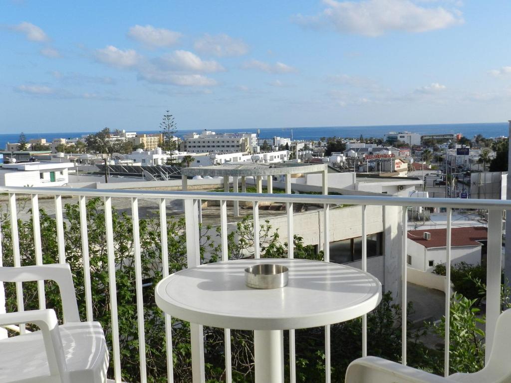 balcón con mesa blanca, sillas y vistas en Elenapa Holiday Apartments, en Ayia Napa