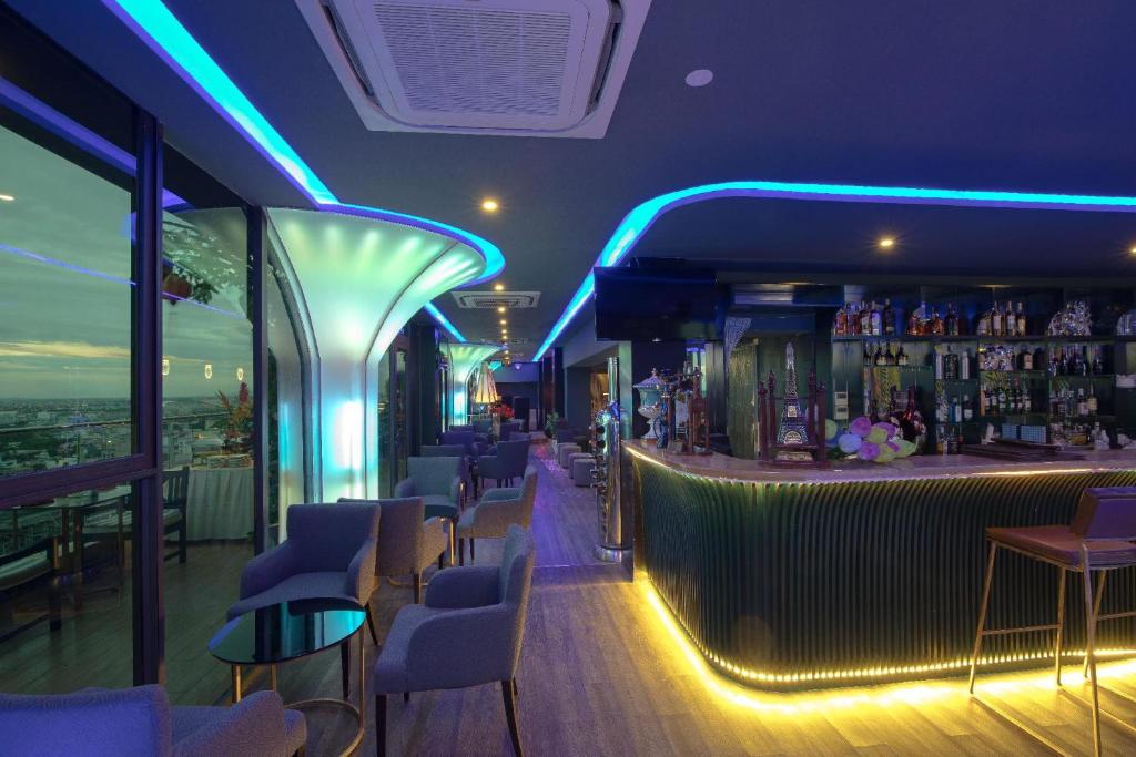 A blue-lit bar lounge with a broad urban view through the windows.