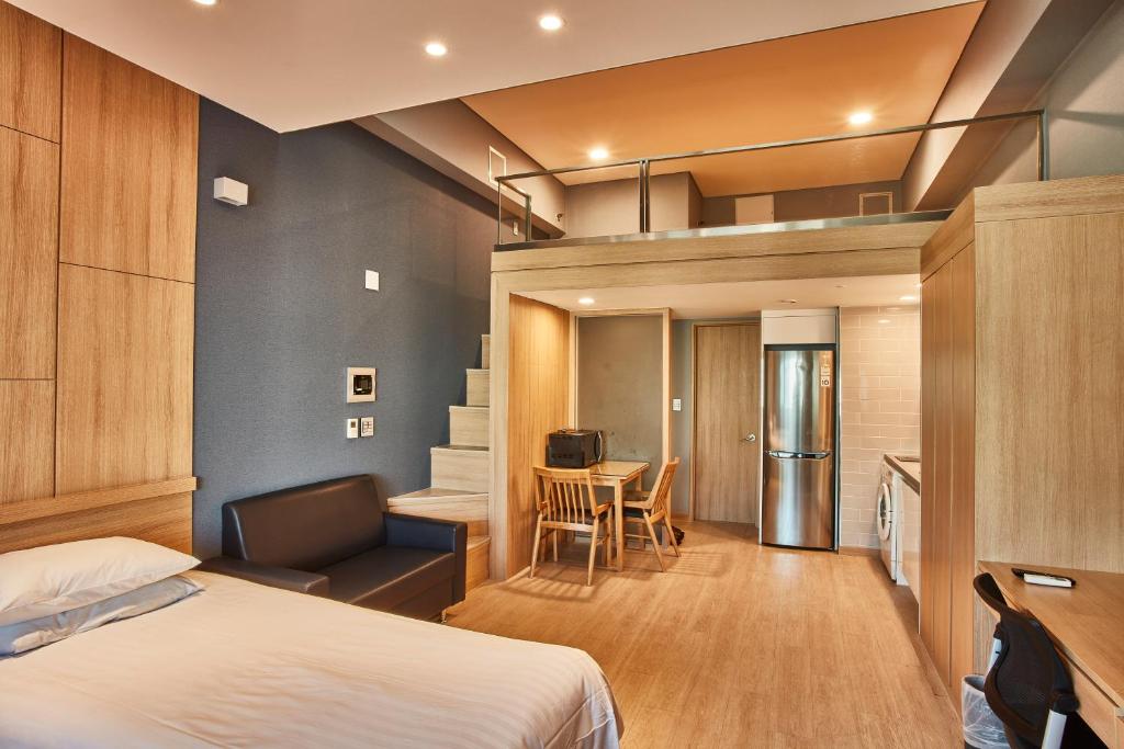 a bedroom with a bed and a desk and a kitchen at Provista Hotel in Seoul