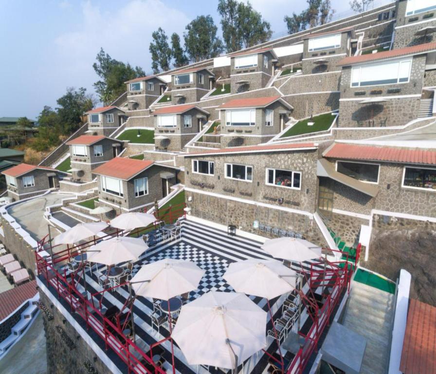 a pool with umbrellas in front of a building at 360 South, Khandala in Lonavala