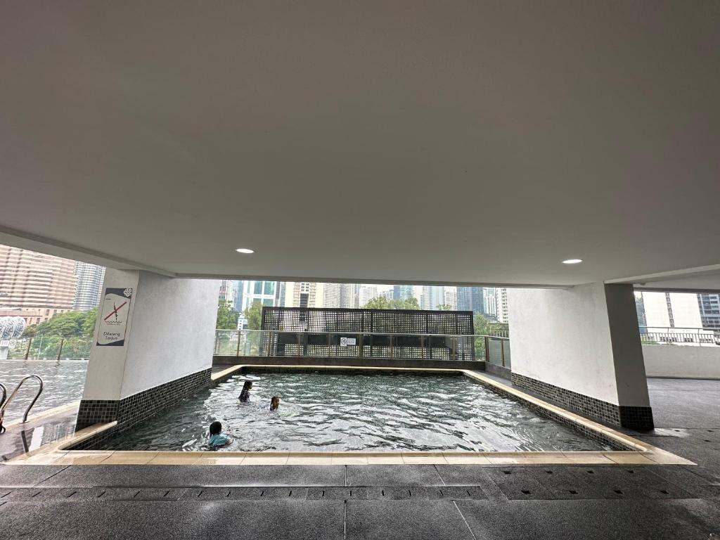 two people swimming in a pool in a building at KLCC Kampung Baru Cottage - Homestay in Kuala Lumpur