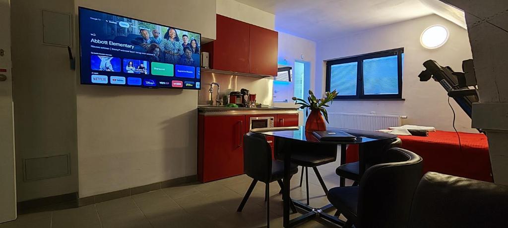 a kitchen with a table and a tv on the wall at Logeerkamer XXL 25 m2 in Zemst