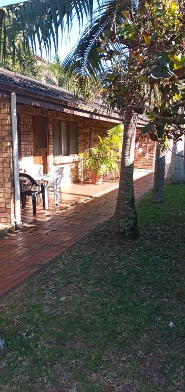 a patio with a table and a tree in front of a building at Flamboyant Apartments in St Lucia