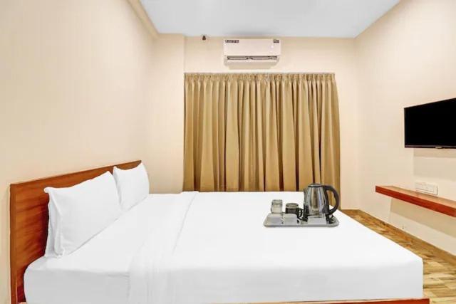 a bedroom with a large white bed and a television at Sri Udupi park phoenix mall in Bangalore