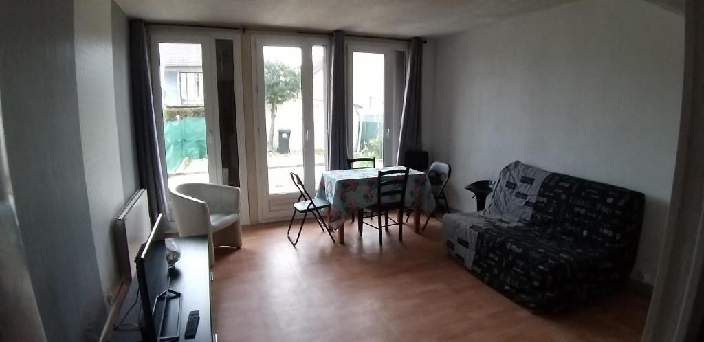 ein Wohnzimmer mit einem Tisch und einem Stuhl in der Unterkunft Maison 2 chambres, terrasse/jardin (proche PARIS) in Argenteuil