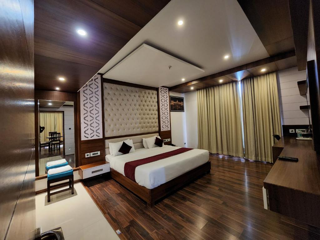 a bedroom with a bed and a table and a chair at Hotel Preethi International in Mysore