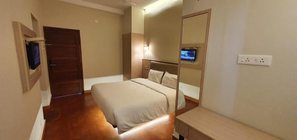 een kleine slaapkamer met een bed en een spiegel bij The Nisha Continental in Kottayam