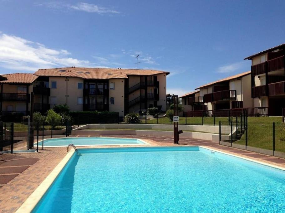 a swimming pool in front of some apartment buildings at V-Landes 01 T2 dans résidence avec piscine face au lac marin in Vieux-Boucau-les-Bains