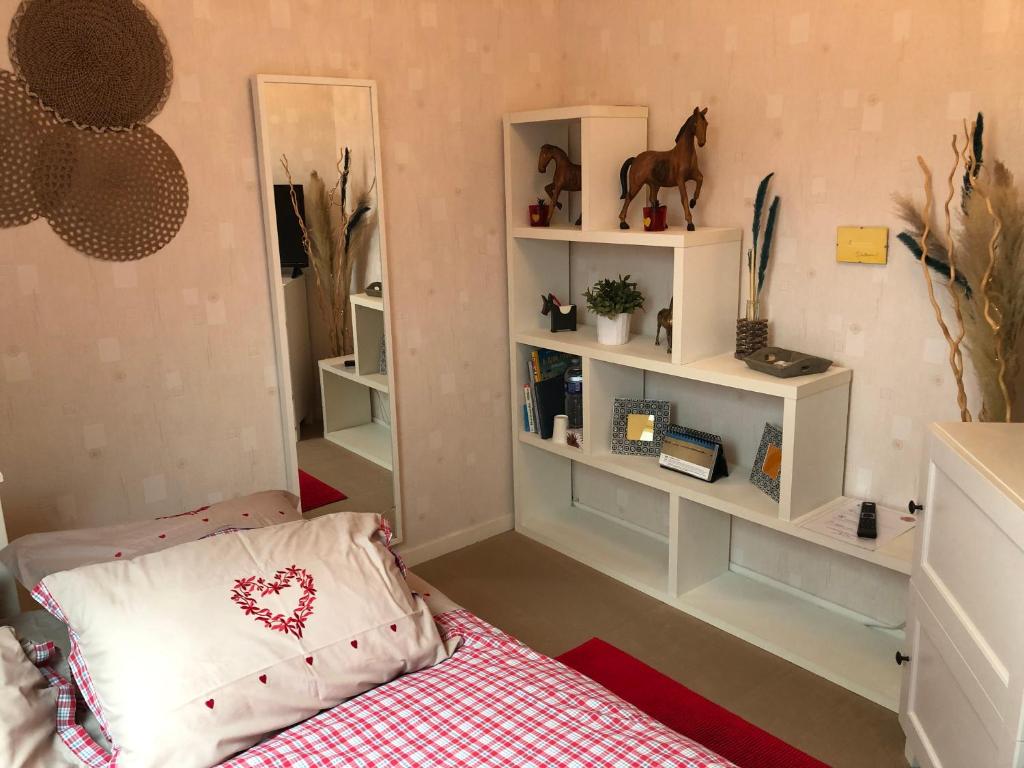 1 dormitorio con cama y estanterías con un caballo en la pared en Coquelicot, en Hermanville-sur-Mer