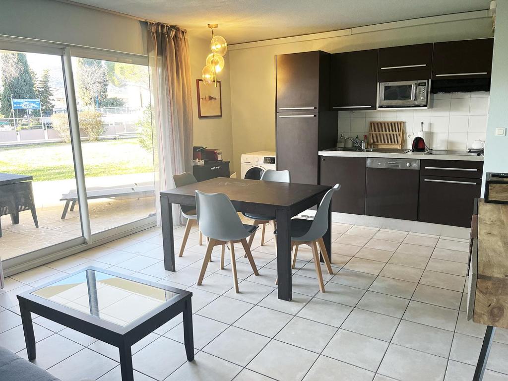 une cuisine et une salle à manger avec une table et des chaises dans l'établissement Appartement 301 avec deux chambres - LES SUITES DE ROBINSON - Résidence avec piscine en bord de Siagne, à Mandelieu-La-Napoule, à Mandelieu-la-Napoule