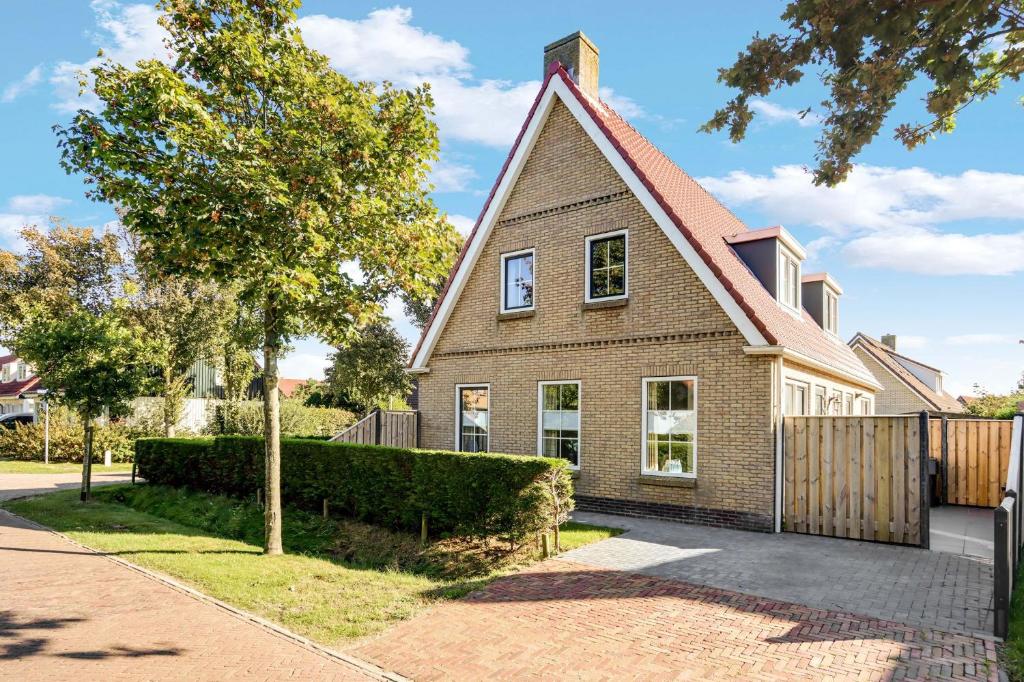 une maison en briques brunes avec une clôture dans l'établissement Vakantiehuis BonBuren, à Buren