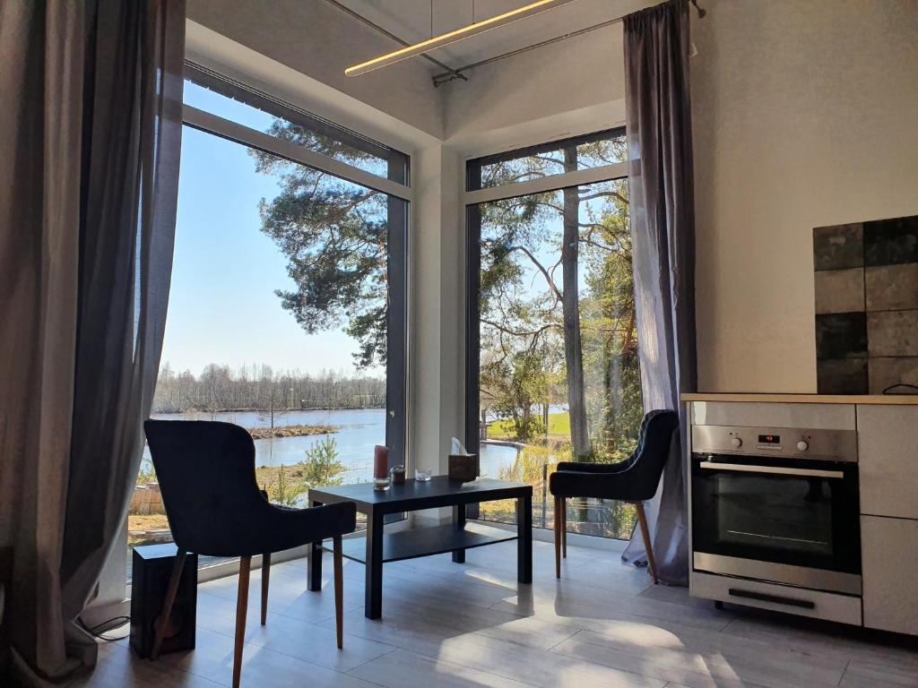 Loft 3 rooms riverside by Gauja.Club - Residences في Gauja: غرفة معيشة مع طاولة وكراسي ونافذة كبيرة