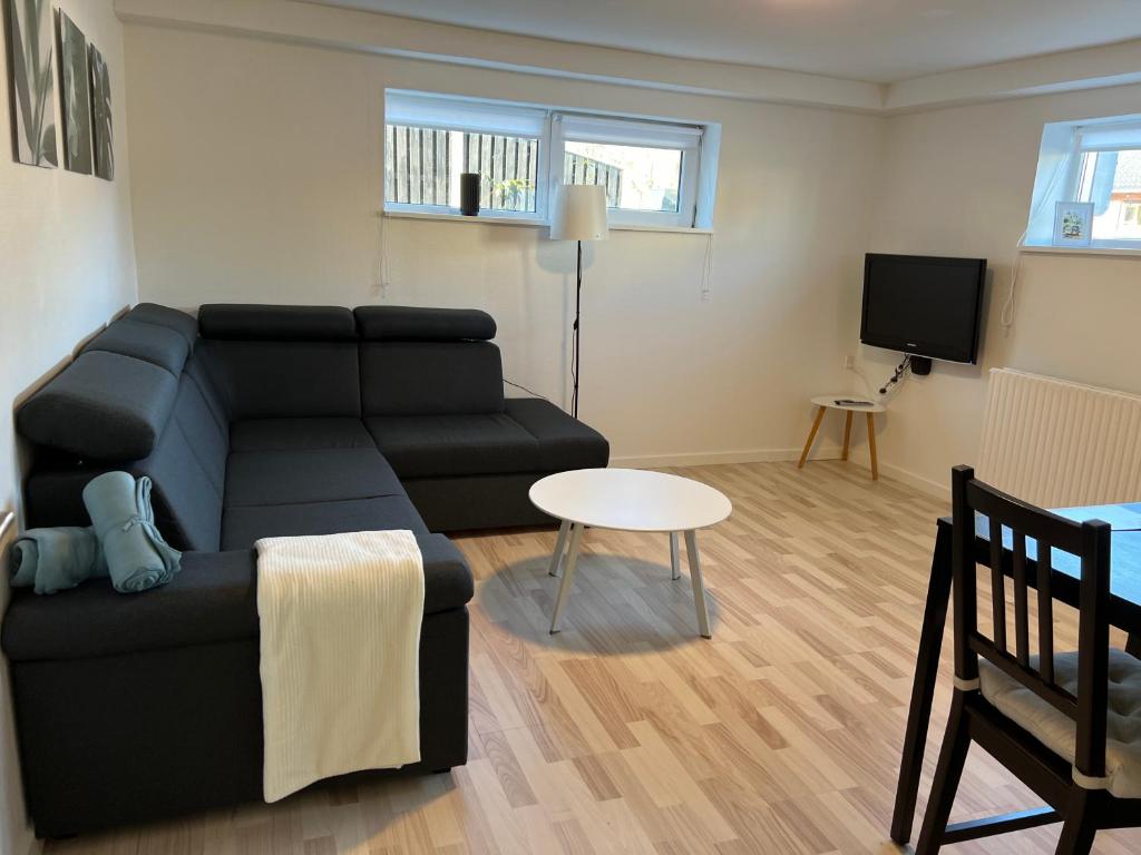 ein Wohnzimmer mit einem schwarzen Sofa und einem Tisch in der Unterkunft Hyggelig & lys kælderlejlighed in Herning