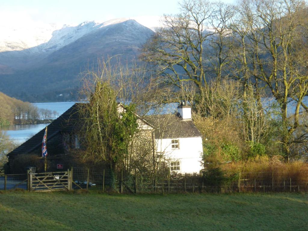 una casa en un campo con un lago y una montaña en Slack Cottage, en Ambleside