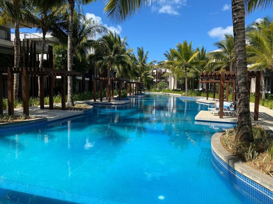 a large pool with palm trees in a resort at LUX APPARTMENT GOLF DE MONT CHOISY in Mont Choisy