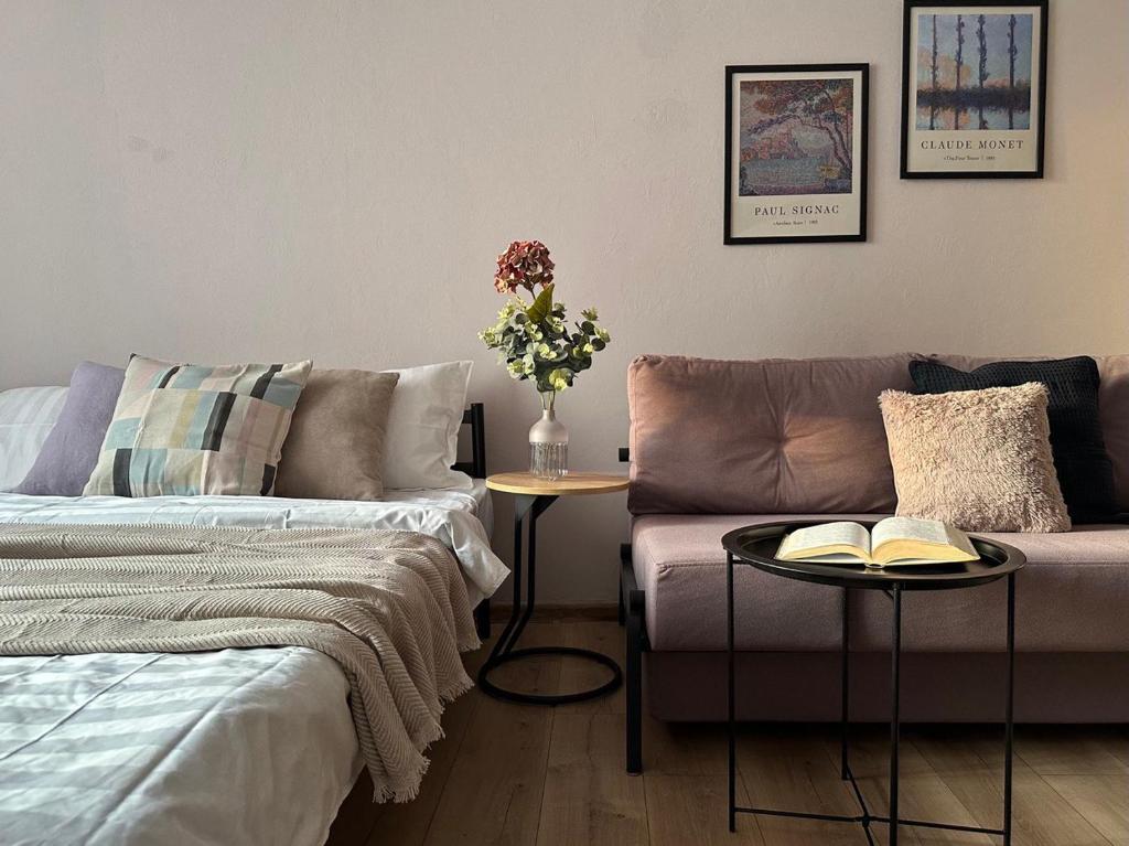 a living room with a couch and a table with books at Студия МЕРЕНГА в центре Алматы in Almaty