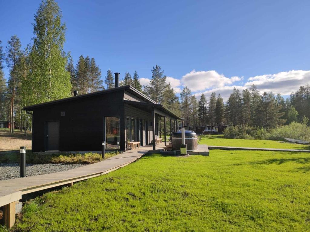 a black building with a walkway in the grass at Norwide - Hossan Lomakeskus in Hossa