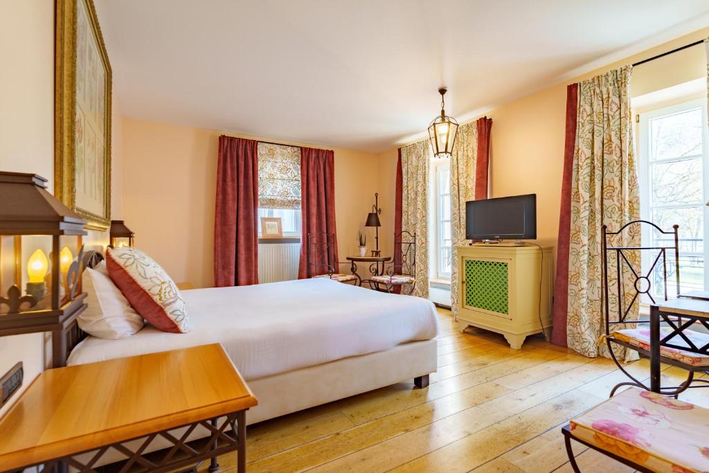 a hotel room with a bed and a tv at Les Jardins d'Anaïs in Luxembourg