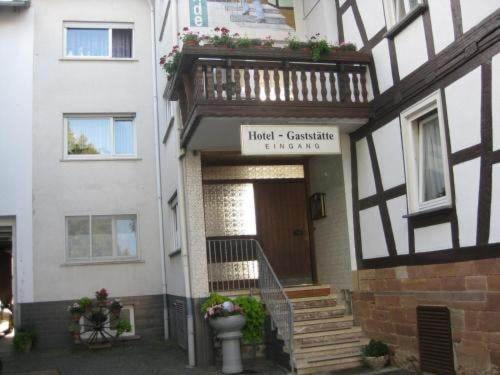 un edificio con puerta y balcón. en Gasthaus zur Linde, en Staufenberg