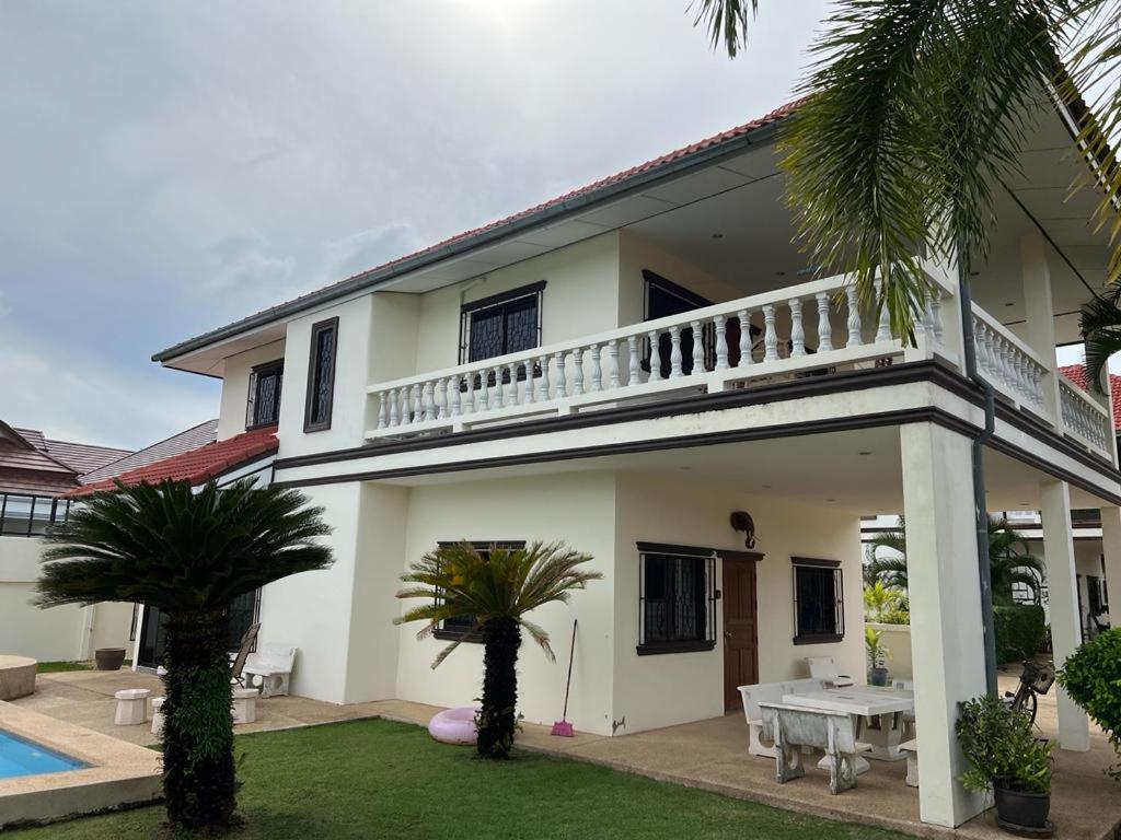 a white house with a balcony and a yard at Dragon Dream 1 D6 Hua Hin with Pool in Cha Am