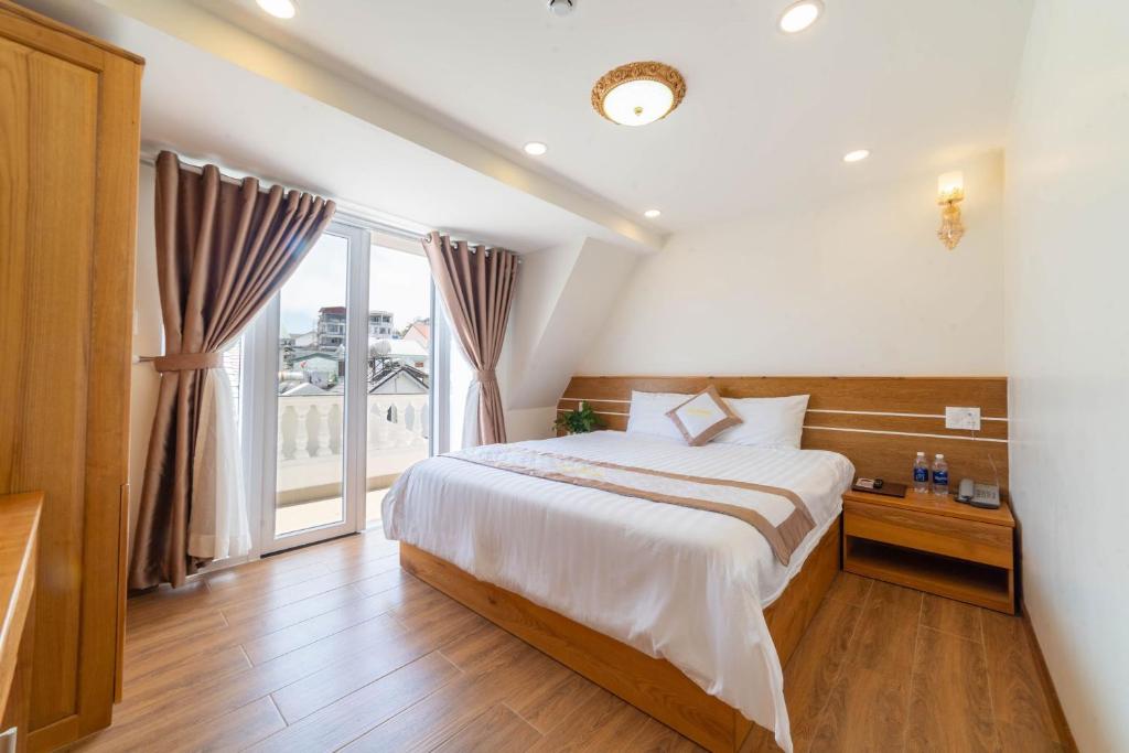 een slaapkamer met een bed en een groot raam bij Cherry House Đà Lạt in Da Lat