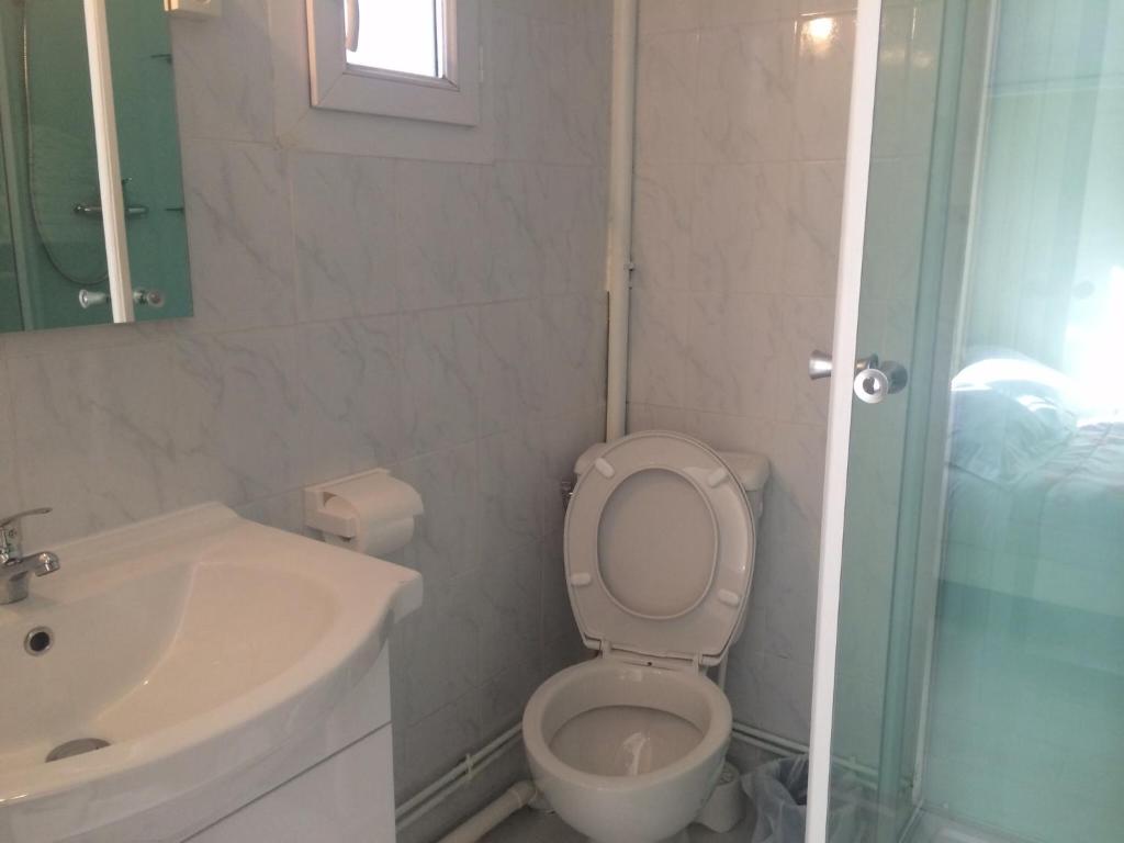 a white bathroom with a toilet and a sink at Hotel Restaurant Tokyo in Trouville-sur-Mer