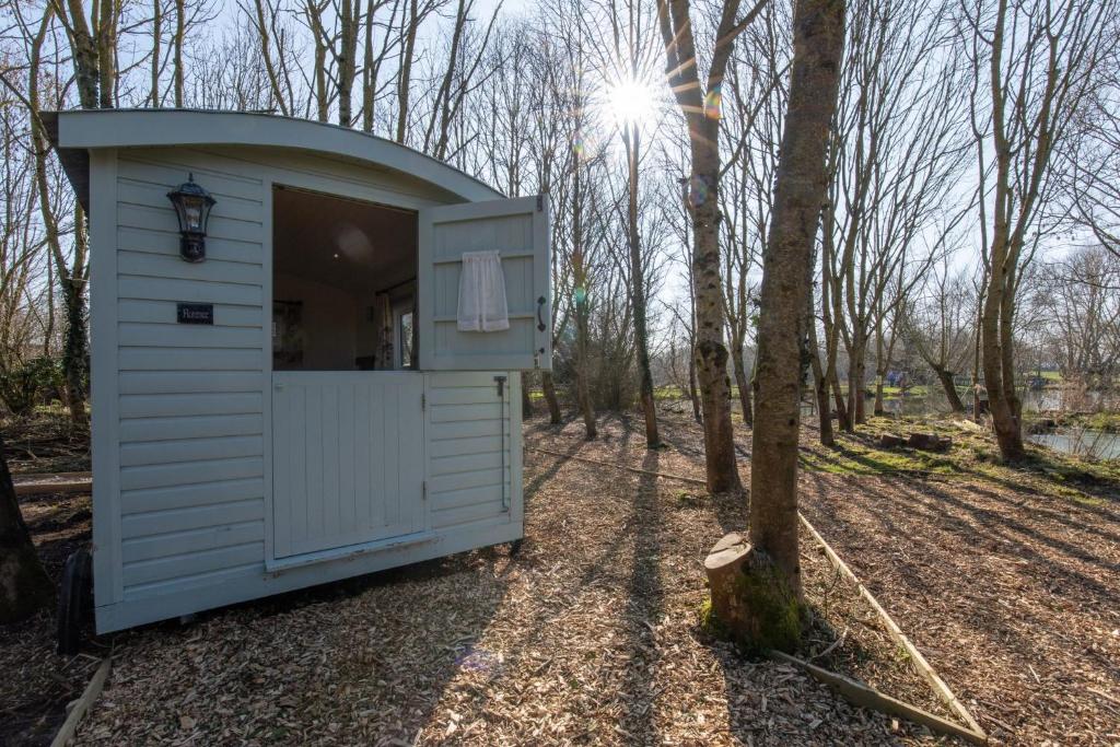 North Bradley的住宿－Fairwood Lakes - Shepherd's Hut with Hot Tub，树林里的一个白色小房子