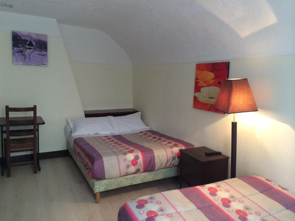 a bedroom with two beds and a lamp and a chair at Hotel Restaurant Tokyo in Trouville-sur-Mer