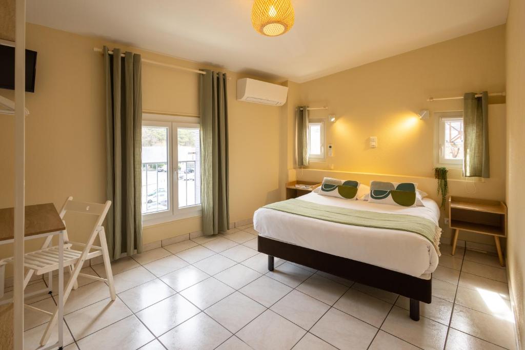 1 dormitorio con 1 cama, mesa y sillas en L'Aptois Hôtel en Apt