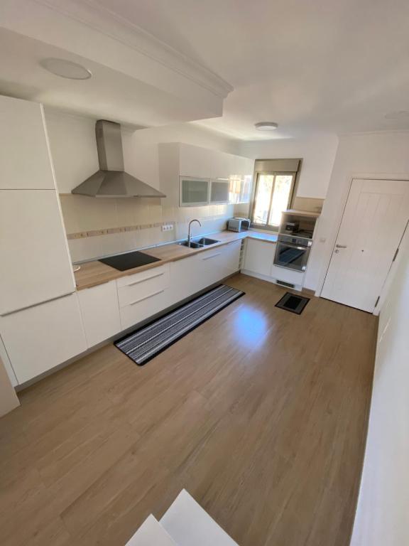 cocina con armarios blancos y suelo de madera en Apartamento Almogaren, en Valsequillo