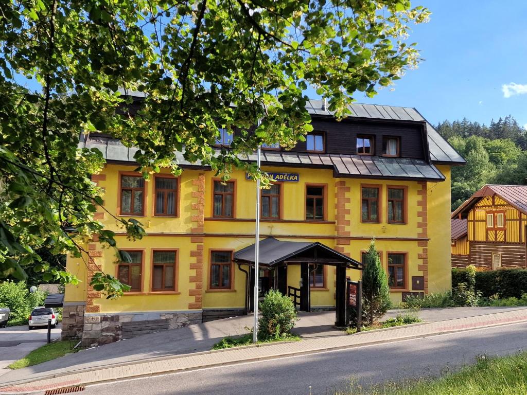 un bâtiment jaune sur le côté d'une rue dans l'établissement Penzion Adélka Janské Lázně, à Janské Lázně