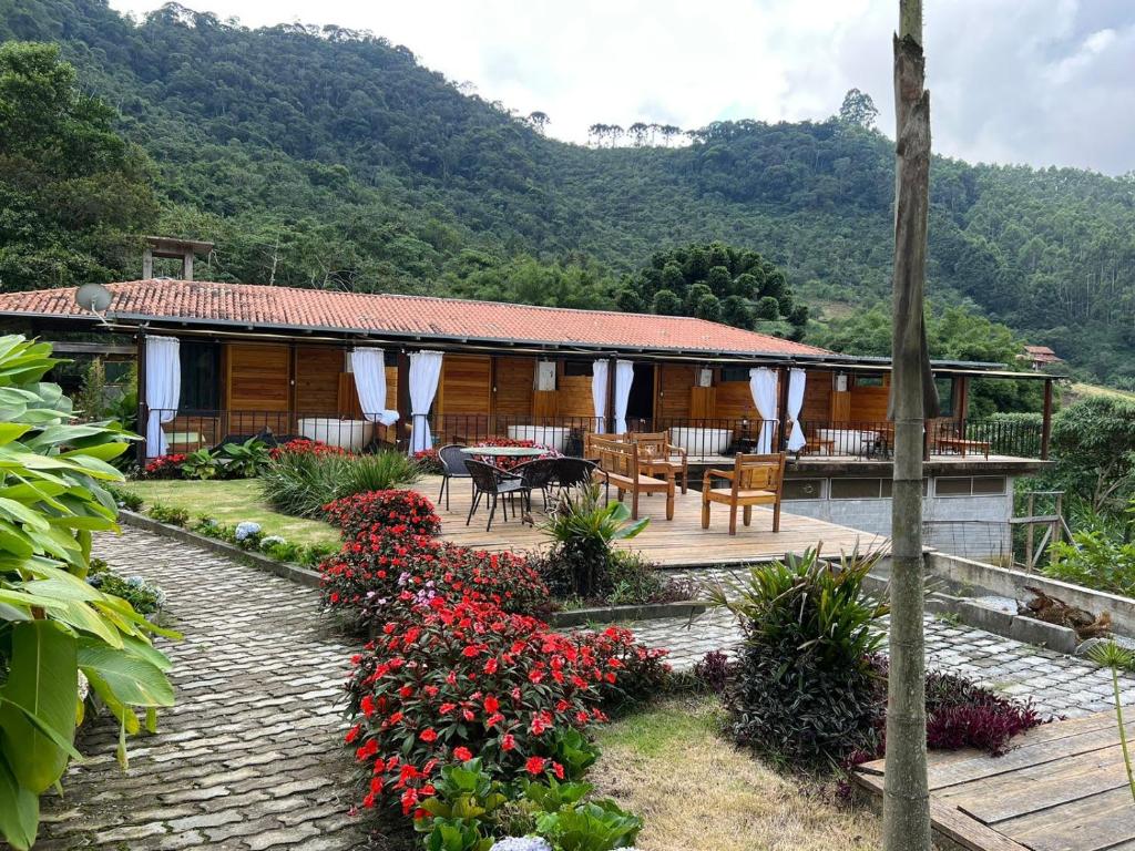 een huis met een patio en een tafel en bloemen bij Pousada Fiori in Nova Friburgo