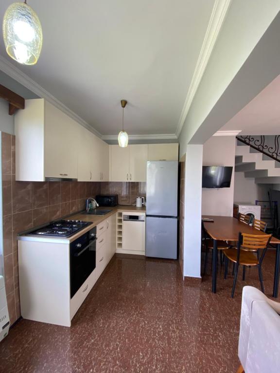 uma cozinha com armários brancos, uma mesa e um frigorífico em Дом на пляже Black sea House em Kobuleti