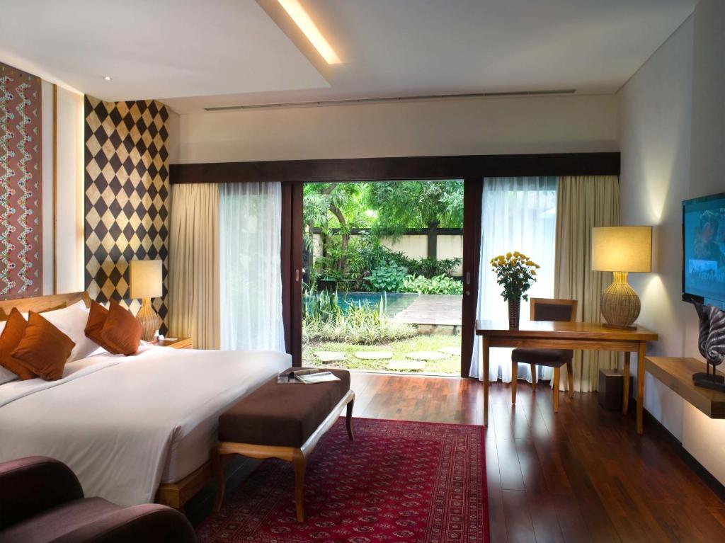a bedroom with a bed and a desk and a large window at Bintang Bali Villa in Kuta