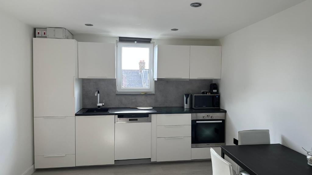 a kitchen with white cabinets and a window at Stunning new 1 bedroom apartment in London