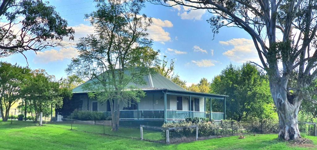a house with a green roof and a tree at Old Schoolmaster's Cottage on the Barrington River in Barrington