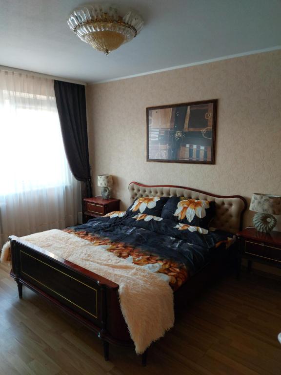 um quarto com uma cama grande e uma janela em Apartamentai šalia parko em Siauliai