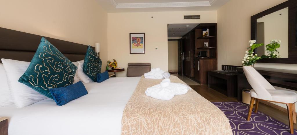 a bedroom with a large white bed with blue pillows at Savoy Le Grand Hotel Marrakech in Marrakesh
